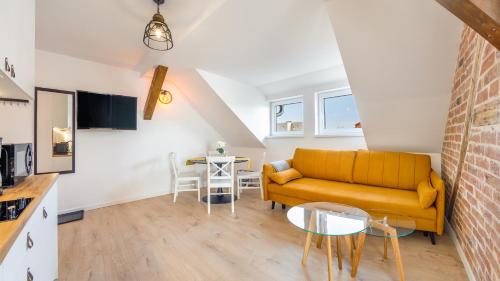 a living room with a yellow couch and a table at Apartamenty Sun & Snow Ustka Centrum in Ustka
