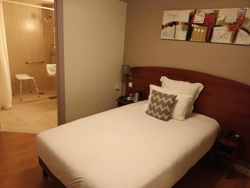 a bedroom with a bed and a bathroom at Hôtel des Arcades de Cachan - Grand Paris Sud in Cachan