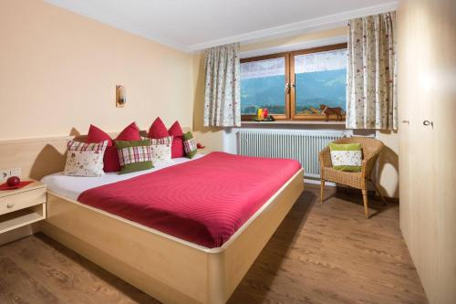 Schlafzimmer mit einem großen Bett mit roter Bettwäsche und einem Fenster in der Unterkunft Ferienwohnung Drachllehen in Schönau am Königssee