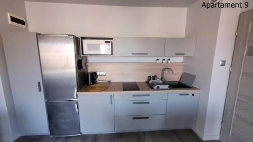 a kitchen with white cabinets and a stainless steel refrigerator at Apartament Rybacka 84/9 in Krynica Morska - Piaski
