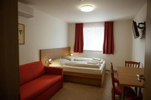 een slaapkamer met een bed en een rode bank bij Penzion Sudomír in Sudoměřice