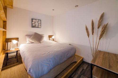 Un dormitorio con una cama blanca y una planta en Apt neuf / tout confort / 7 mn d'Auxerre / Netflix 