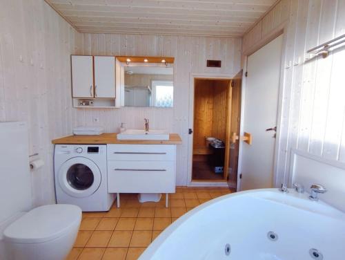 y baño con bañera, lavabo y lavadora. en Ferienhaus Wackerama in Gelting, en Gelting