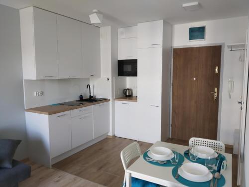 kuchnia z białymi szafkami i stołem z płytami w obiekcie Apartament Kapitalny przy porcie w Kołobrzegu z rowerownią i placem zabaw w Kołobrzegu