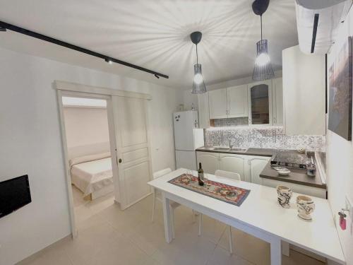 eine weiße Küche mit einem Tisch und einem Bett in der Unterkunft Casa Vacanze Margherita in Castellammare del Golfo