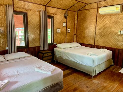 a bedroom with two beds and two windows at ครัวพาร์3ริเวอร์ไซด์แอนด์รีสอร์ท 