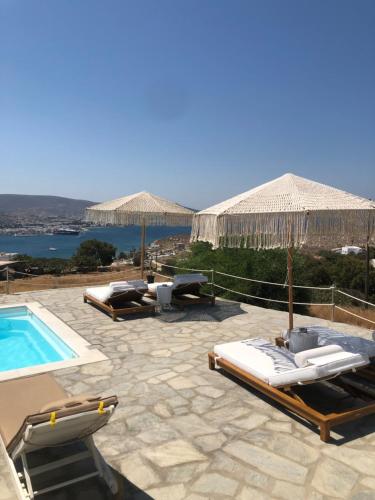 a pool with chaise lounges and umbrellas at Blue Bay Heliolithos in Parikia