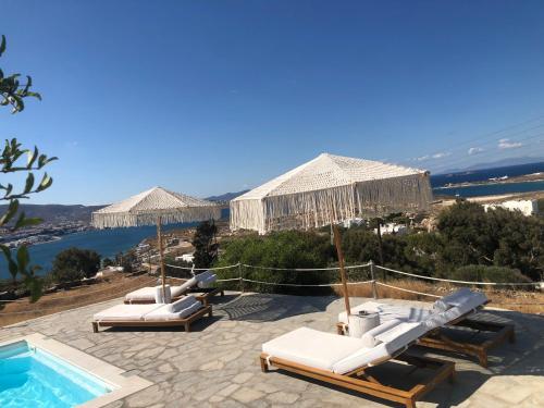 a pool with lounge chairs and umbrellas on a resort at Blue Bay Heliolithos in Parikia