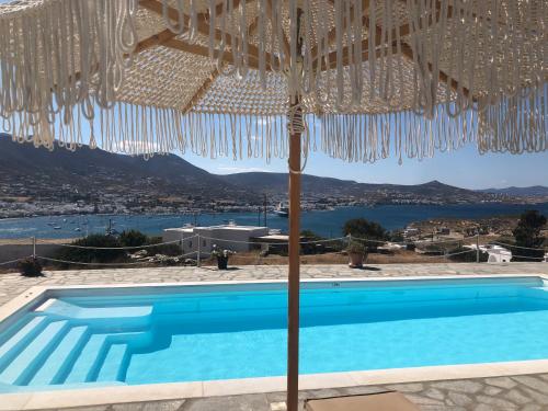 a villa with a swimming pool and an umbrella at Blue Bay Heliolithos in Parikia