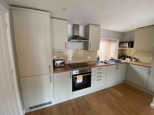 a kitchen with white cabinets and a wooden floor at Cosy Homely Apartment close to Lincoln City Centre in Lincoln