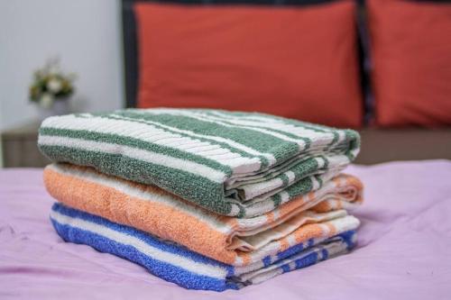 a stack of towels sitting on top of a bed at Bunut Centre Stay in Bandar Seri Begawan