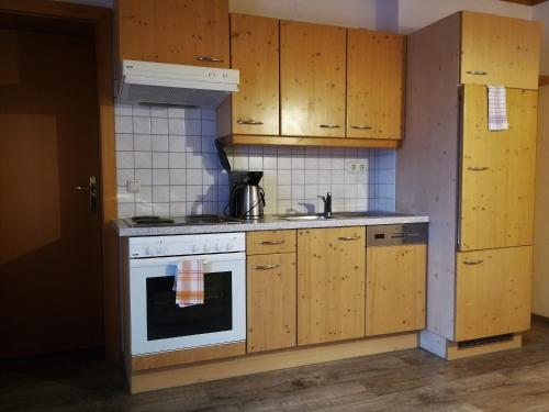 a kitchen with a white stove and wooden cabinets at Appartement-Pension Familie Gewessler in Bad Mitterndorf