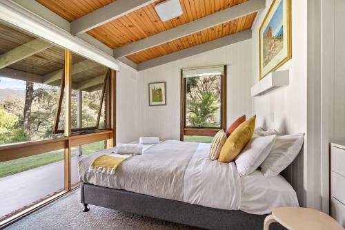 a bedroom with a bed and a large window at Kiewa Country Cottages in Mount Beauty