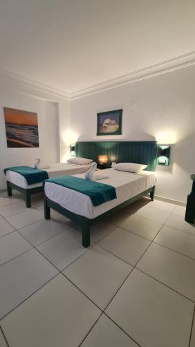two beds in a large room with white tile floors at Zak Inn in Hurghada