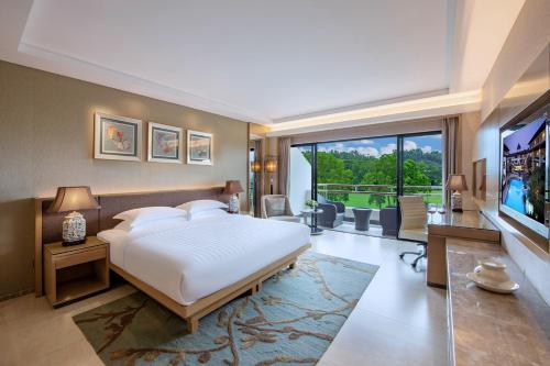 a bedroom with a large white bed and a television at Mission Hills Hotel Resorts Shenzhen in Bao'an