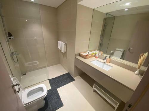 uma casa de banho com um lavatório, um WC e um espelho. em Home-like modern 1 bedroom apartment SeaWorld view em Abu Dhabi