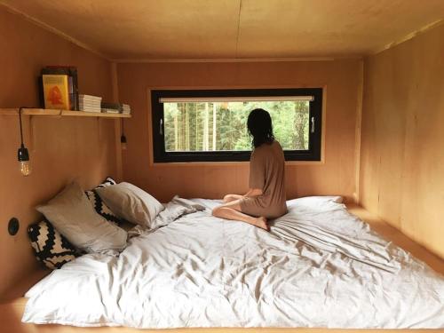 a woman sitting on a bed looking out a window at Včelíny Želiv in Želiv