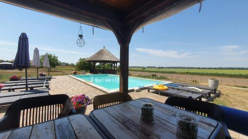 a wooden table with chairs and a swimming pool at Tisza White House in Tiszaszőlős