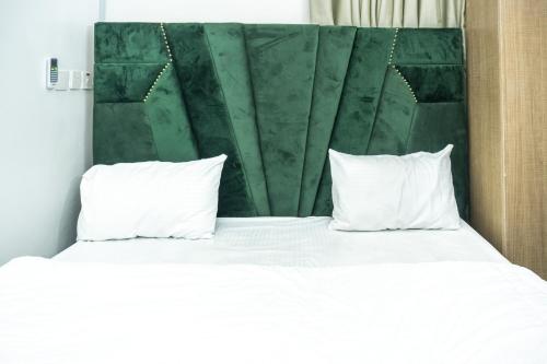 a bed with white pillows and a green headboard at Lakeview 2-Bed-Apt With Amazing Views In Every Direction in Amuwo