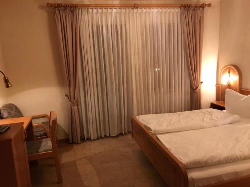 a bedroom with a bed and a desk and a window at Linde Diersburg Stammhaus in Diersburg