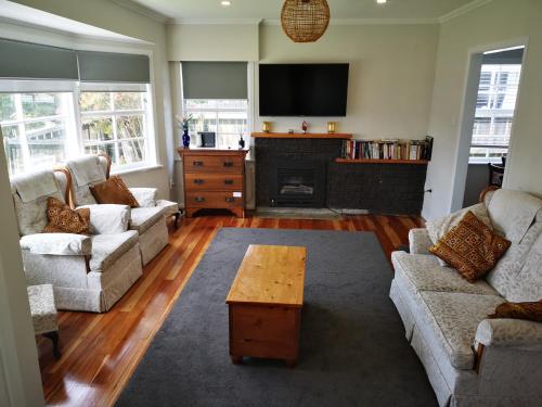 a living room with two couches and a fireplace at Cheerful 4 Bedroom Holiday Home (Sleeps 7) in Rotorua