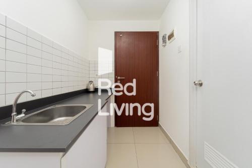 a bathroom with a sink and a red living sign on the door at RedLiving Apartemen Sayana - Sentra Jaya in Bekasi