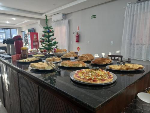 um buffet com muitos tipos diferentes de pizzas e uma árvore de Natal em Sognare Hotel em Caçador
