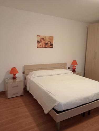 a bedroom with a white bed and two pictures on the wall at Appartamento Malcontenta in Mira