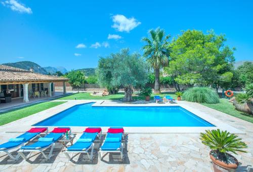 basen z niebieskimi i czerwonymi krzesłami obok domu w obiekcie Owl Booking Villa Can Pou - Luxury Holidays in Royal Gardens w mieście Pollença