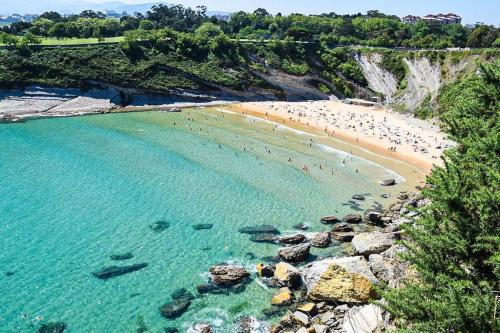 a group of people on a beach in the water at Bajo con terraza a 5 min de la playa (3 hab-6 per) in Santander