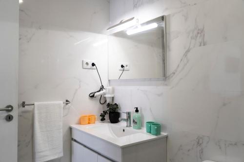 a white bathroom with a sink and a mirror at Almada Downtown 103 in Porto