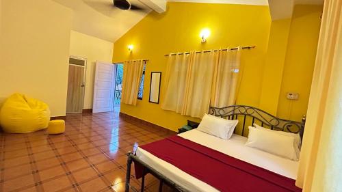 a bedroom with a bed and a yellow wall at Muffys Guest House in Arpora