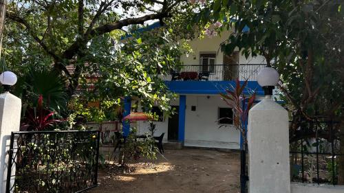 a house with a gate and a blue and white building at Muffys Guest House in Arpora