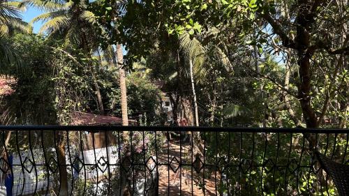 a black fence with trees in the background at Muffys Guest House in Arpora