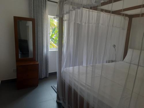 a bedroom with a canopy bed with a window at Hotel Paradiso, in Unawatuna