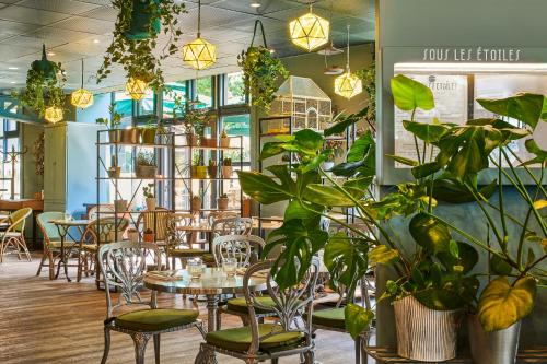 un restaurante con mesas, sillas y plantas en ibis Paris Bastille Opera, en París