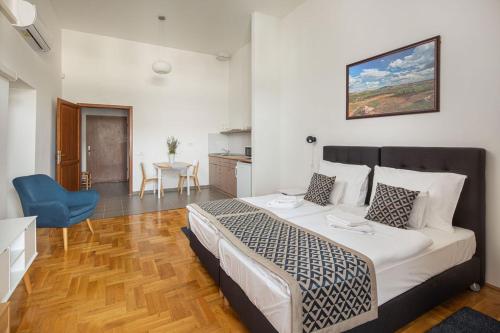 a bedroom with a large bed and a blue chair at Grossmann Ház in Mád