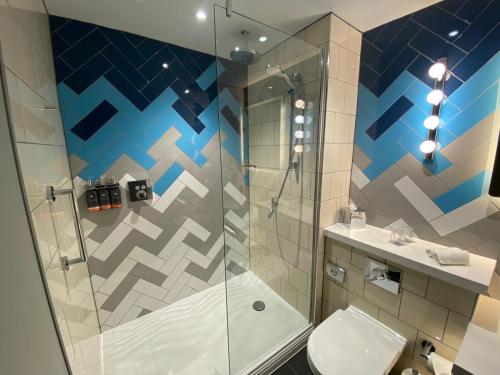 a bathroom with a shower and a toilet and a sink at Hotel Indigo - Cardiff by IHG in Cardiff