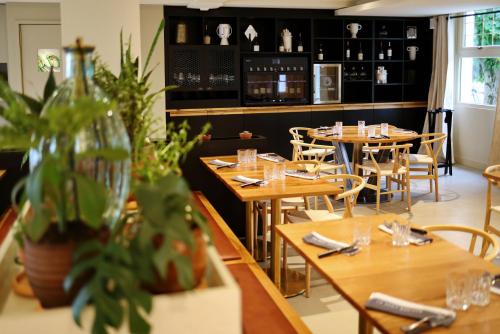 a restaurant with wooden tables and chairs and plants at Logis Hôtel & Restaurant Le Vert Bocage in Franqueville-Saint-Pierre