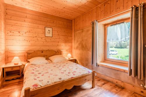 a bed in a wooden room with a window at Gîte des Cascades in Sixt