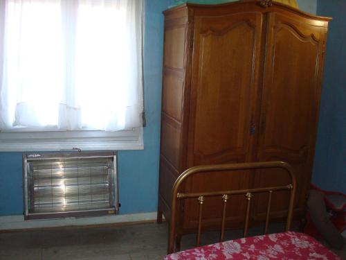 ein Schlafzimmer mit einem Holzschrank und einem Fenster in der Unterkunft Chalet appartement in Lille
