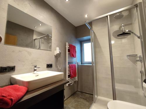ein Bad mit einem Waschbecken und einer Dusche in der Unterkunft Appartements Pfausler in Oetz