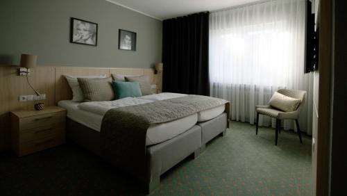 een slaapkamer met een bed met een stoel en een raam bij Landgasthaus Lenniger in Büren