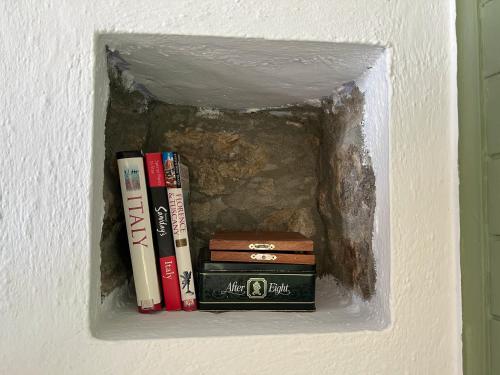 a shelf with books on a wall at Agriturismo La Collina degli Scoiattoli in Cravanzana