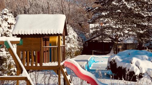 a snow covered yard with a house and a swimming pool at Hotel Slatina in Lipova Lazne