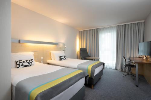 a hotel room with two beds and a desk at Holiday Inn Express Nürnberg-Schwabach in Schwabach
