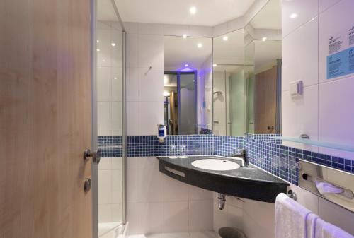 ein Bad mit einem Waschbecken und einem Spiegel in der Unterkunft Holiday Inn Express Nürnberg-Schwabach in Schwabach