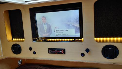 TV de pantalla plana al lado de un autobús en Wallace Teardrop Caravan for Hire from ElectricExplorers, en Hawkshead