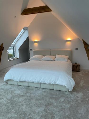 une chambre avec un grand lit blanc dans un grenier dans l'établissement Ty Dag - Grande Terre, à Roscoff