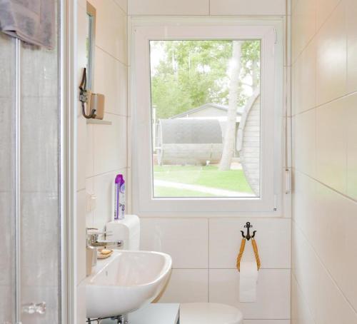 a white bathroom with a sink and a window at Ferienhäuser Kiebitzsee in Falkenberg